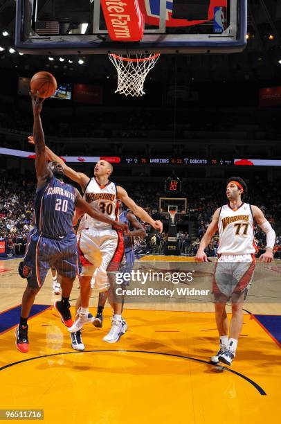 Raymond Felton of the Charlotte Bobcats shoots a layup against Stephen Curry and Vladimir Radmanovic of the Golden State Warriors during the game at...