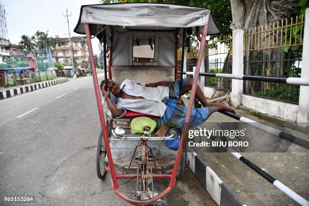 An Indian rickshaw puller sleeps on his rickshaw amid rising temperatures in Guwahati on June 1, 2018.