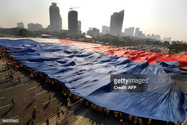 Supporters of Philippine religious leader and presidential candidate Eddie Villanueva unfurl a huge national flag to signal the start of his campaign...