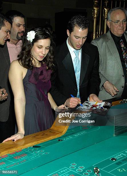 New York Rangers forward Ryan Callahan signing a photo while his girlfriend Kyla Allison waits her turn at the craps table during casino night to...