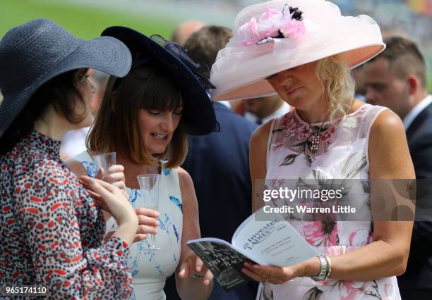 Racegoers read the official race programme during Ladies Day of the Investec Derby Festival at Epsom Downs on June 1, 2018 in Epsom, England.