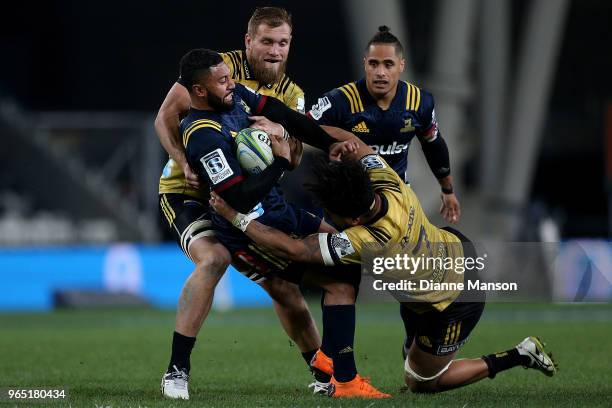 Lima Sopoaga of the Highlanders is tackled by Brad Shields and Ardie Savea of the Hurricanes during the round 16 Super Rugby match between the...