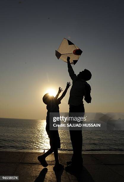 An Indian man and a child fly a kite by the sea in Mumbai on January 14, 2009. Makar Sakranti, the Hindu kite festival, marks the transition of the...