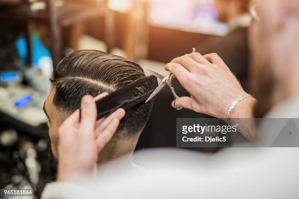 vista posteriore del giovane che sta ottenendo un taglio di capelli moderno. - stile di capelli foto e immagini stock