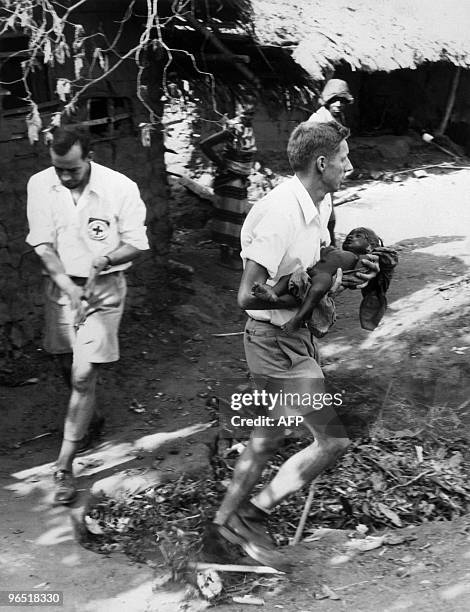 Red Cross volunteer carries a baby in a Biafran village, 11 January 1970, at the end of the Biafra war. The war opposing Biafra secessionnist tribes...