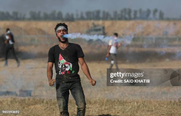 Palestinian protester holds a tear gas canister in his mouth during a demonstration along the border with Israel east of Khan Yunis in the southern...