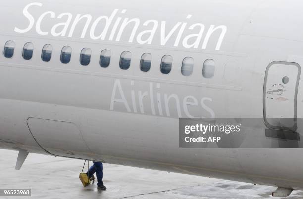 The legs of a technichan emerge under one of the SAS MD-82 aircrafts parked at a gate on Terminal 5 at Arlanda airport north of Stockholm, Sweden, on...