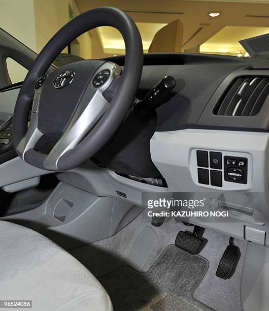 This picture shows a steering wheel, brake pedal, and accelerator of the latest Toyota Prius hybrid vehicle on display at the company's showroom in...