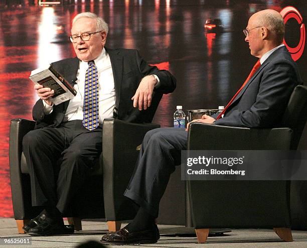 Warren Buffett, chairman and chief executive officer of Berkshire Hathaway Inc., left, holds a copy of "On The Brink" by Henry Paulson, former U.S....