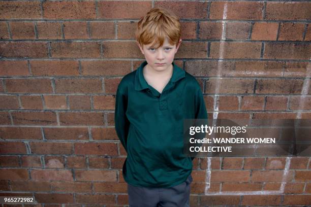 portrait of a frowning australian public school boy against a brick wall. - guidelines of cultural politics stock pictures, royalty-free photos & images