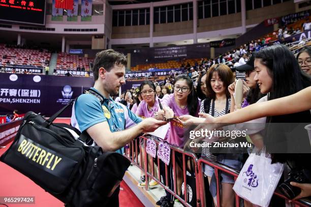 Timo Boll of Germany signs for the crowd after the men's singles match Round of 16 compete with Liang Jingkun of China during the 2018 ITTF World...