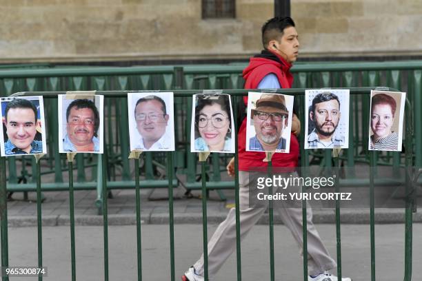 Man walks past pictures of members of the press during a protest against the murder or disappearance of more than 140 journalists and...