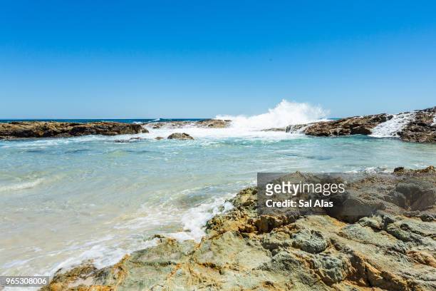 waves crashing on rocks on clear sky and torquoise water - moreton island stockfoto's en -beelden