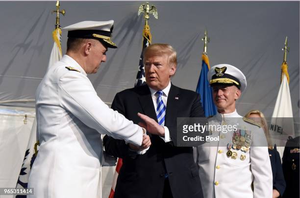 President Donald Trump congratulates Adm. Karl L. Schultz as Adm. Paul F. Zukunft looks on during a U.S. Coast Guard Change-of-Command Ceremony on...