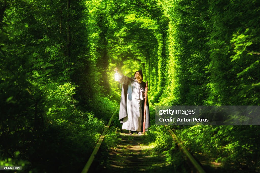 Wizard with a lantern in a tunnel of green forest
