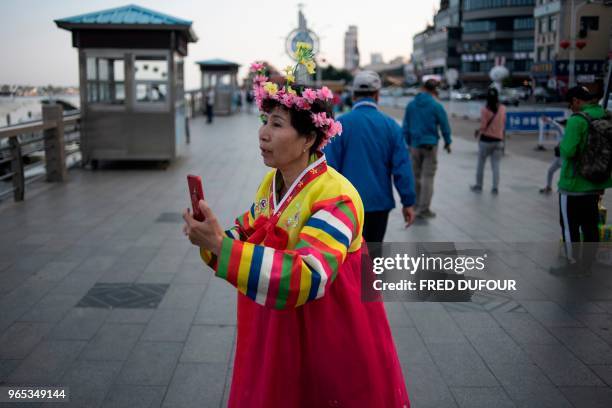 Chinese tourist wearing a traditional North Korean costume, takes pictures over the banks of the Yalu River in the Chinese border town of Dandong, in...