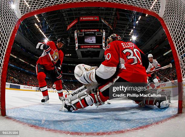 Brian Elliott of the Ottawa Senators kicks out a pad save with teammate Filip Kuba trying to get control of the rebound in a game against the Calgary...