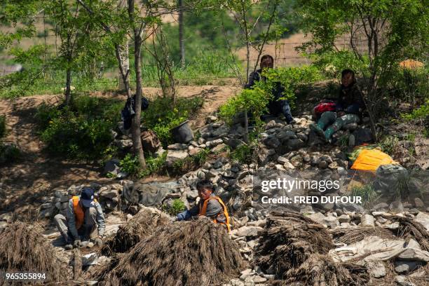 North Korean workers are seen, resting on the bank of the Yalu river near the North Korean town of Sinuiju opposite the Chinese border city of...