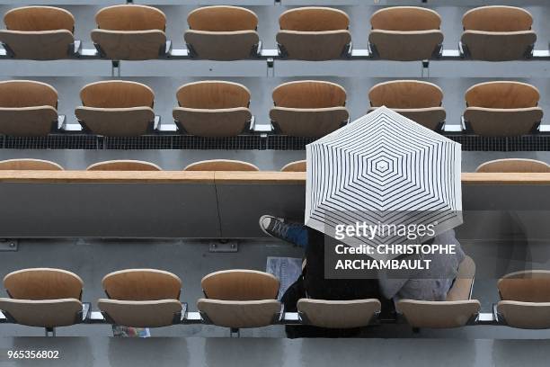 Spectators shelter under an umbrella during a rain delay in the men's singles third round match between France's Gael Monfils and Belgium's David...
