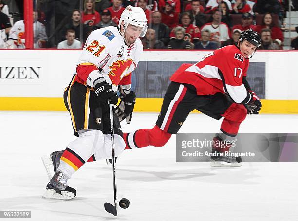 Christopher Higgins of the Calgary Flames skates the puck hard to the net against Filip Kuba of the Ottawa Senators at Scotiabank Place on February...