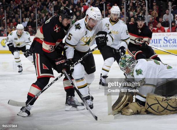 Goalie Marty Turco of the Dallas Stars covers the puck as teammate Matt Niskanen keeps Dave Bolland of the Chicago Blackhawks back during the game on...