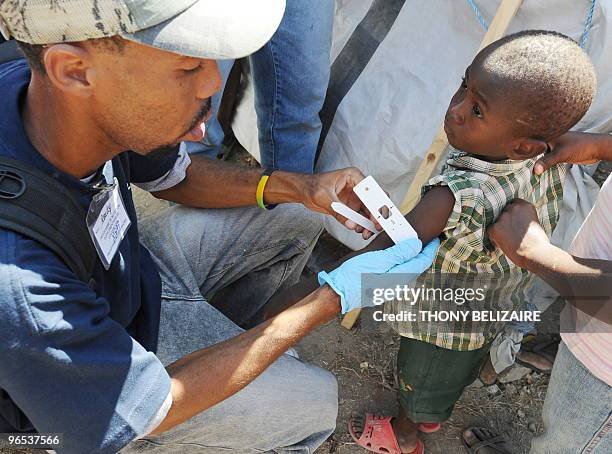 An aid worker tags a little boy on February 9, 2010 at Croix des Bouquets near Port-au-Prince where the World Food Programm has set up a distribution...