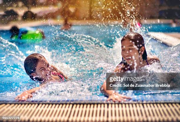 sisters having fun in a swimming pool on a beautiful sunny day - tween girls hot imagens e fotografias de stock