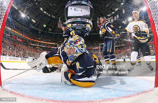 Ryan Miller of the Buffalo Sabres reaches for the puck in front of teammate Henrik Tallinder and Steve Begin of the Boston Bruins on February 9, 2010...