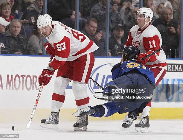 Alexander Steen of the St. Louis Blues goes airborn between Johan Franzen and Daniel Cleary of the Detroit Red Wings on February 9, 2010 at Scottrade...