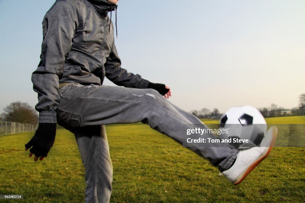 A young male practices his football skills