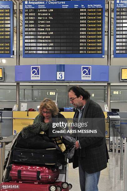 Passengers stand in front of a departure announcement board of the Athens international airport during a 24 hour strike on February 10, 2010....