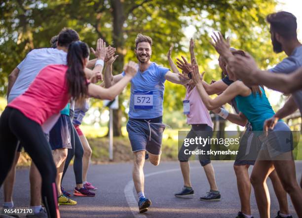 happy marathon runner greeting group of athletes at finish line. - finishing line stock pictures, royalty-free photos & images