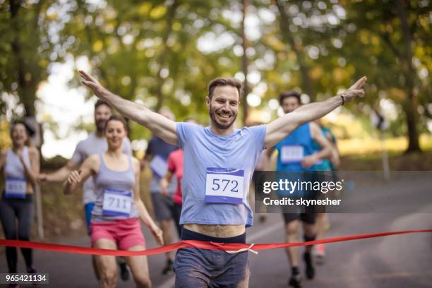 successful marathon runner crossing finish line in nature. - running marathon finish line stock pictures, royalty-free photos & images