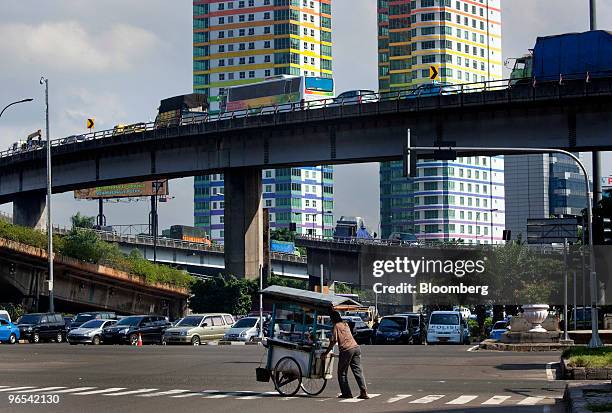 Man pushes his food cart through an intersection in Jakarta, Indonesia, on Wednesday, Feb. 10, 2010. Indonesia's economy grew at the fastest pace in...