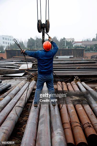 Chinese worker gets a lift as he uploads the steel pipes at a yard in Huaibei, east China's Anhui province on February 9, 2010. China said that its...