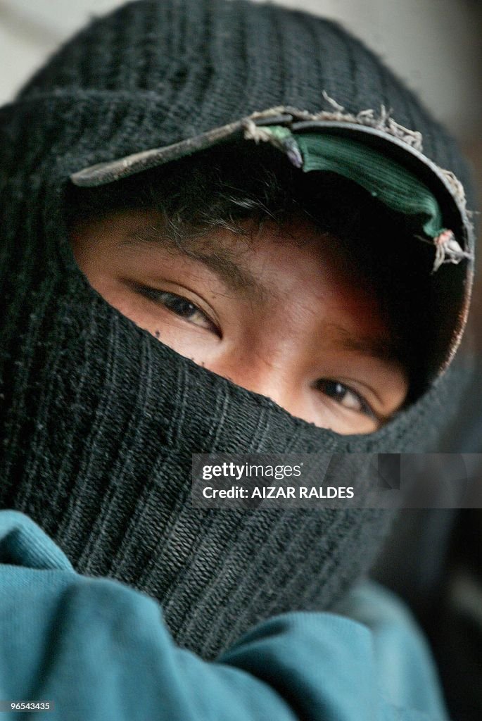 A shoeshiner boy wearing a balaclava sta