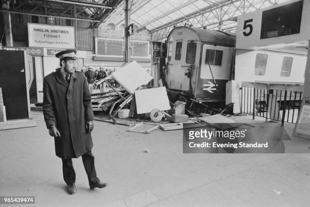 Police officer standing near the wreckage of 'Hastings 6B DEMU 1032' train, which crashed on Charing Cross Station concourse, London, UK, 11th...