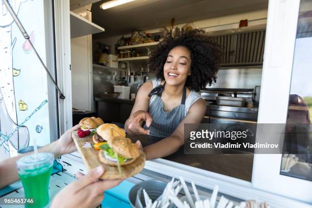 customer taking burgers from food van - food festival imagens e fotografias de stock
