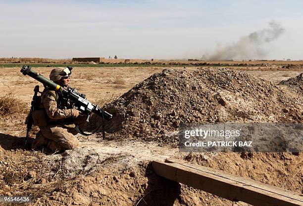 Marine holds a rocket launcher MK153 as he hides behind a sand dune as smoke billows from a mine explosion in a farmland area in the north east of...