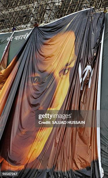 Workers remove a huge poster advertising the controversial Indian movie 'My Name is Khan' featuring film actor Shah Rukh Khan in Mumbai on February...