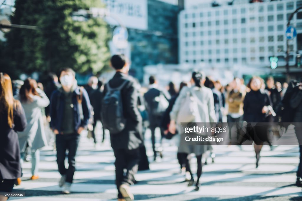 Busy commuters crossing street in downtown district during office rush hours