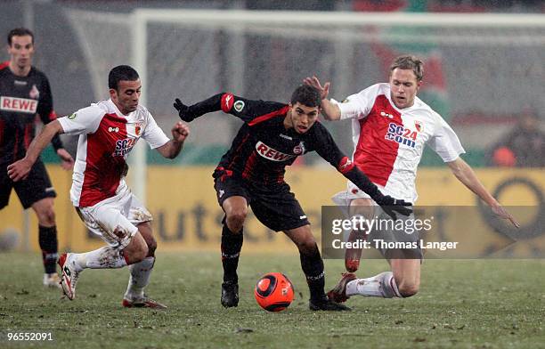 Youssef El-Akchaoui and Jens Hegele of Augsburg and Adil Chihi of Cologne battle for the ball during the DFB Cup quarterfinal match between FC...