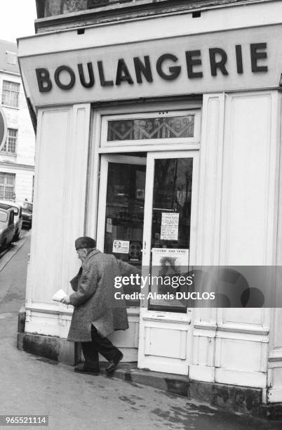 Homme agé sortant d'une boulangerie à Paris en janvier 1986, France.