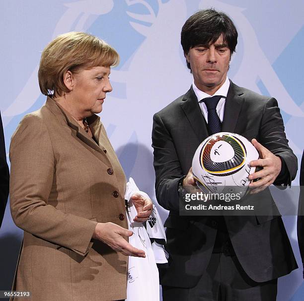 German Chancellor Angela Merkel receives the official FIFA World Cup 2010 ball by Head coach Joachim Loew of the German football national team at...