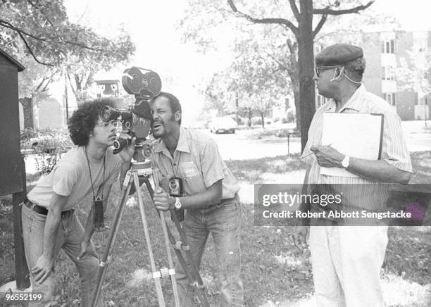On the right, film director Carlton Moss directs a film; Robert Abbott Sengstacke looks through the film camera while a student from Fisk...