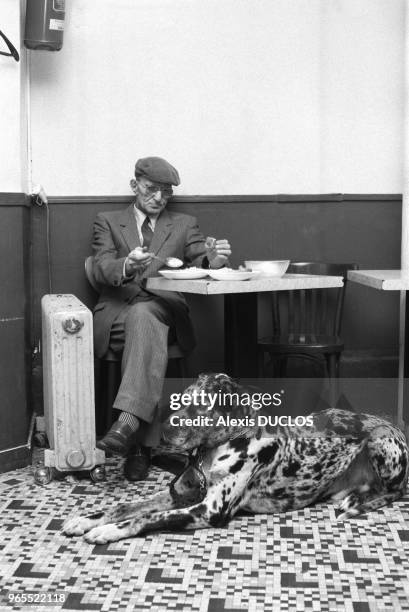 Homme agé assis dans un café avec son chien à Paris en janvier 1986, France.