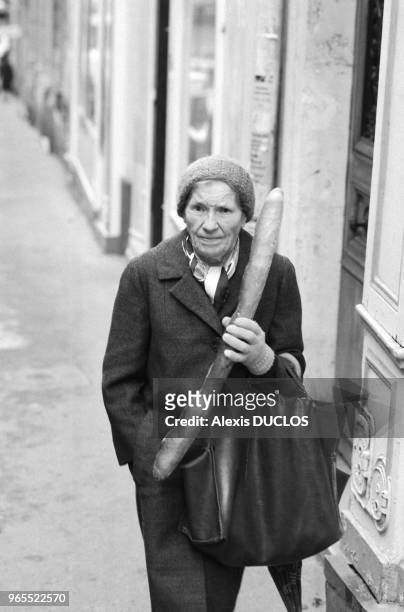 Femme agée tenant une baguette de pain à Paris en janvier 1986, France.