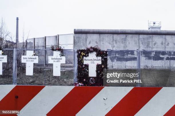 Des croix sur lesquelles sont inscrits les noms des morts sont accrochées à un grillage devant le mur de Berlin, en Allemagne de l'Ouest le 15 mai...