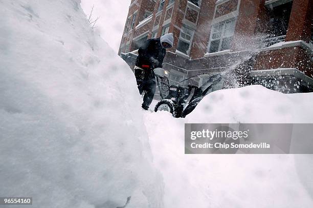 Maintence worker uses a snow blower to clear the sidewalk as snow falls February 10, 2010 in Takoma Park, Maryland. The capital area was crippled...