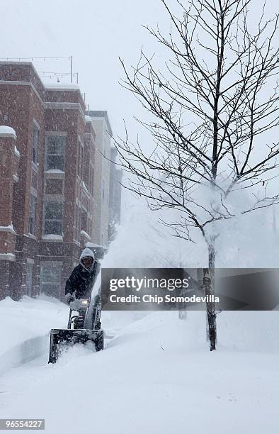 Maintence worker uses a snow blower to clear the sidewalk as snow falls February 10, 2010 in Takoma Park, Maryland. The capital area was crippled...